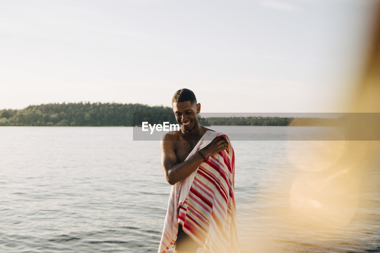 Smiling man wiping with towel after swimming in lake