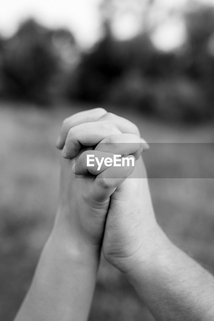 Close-up of bride and groom with clasped hands outdoors