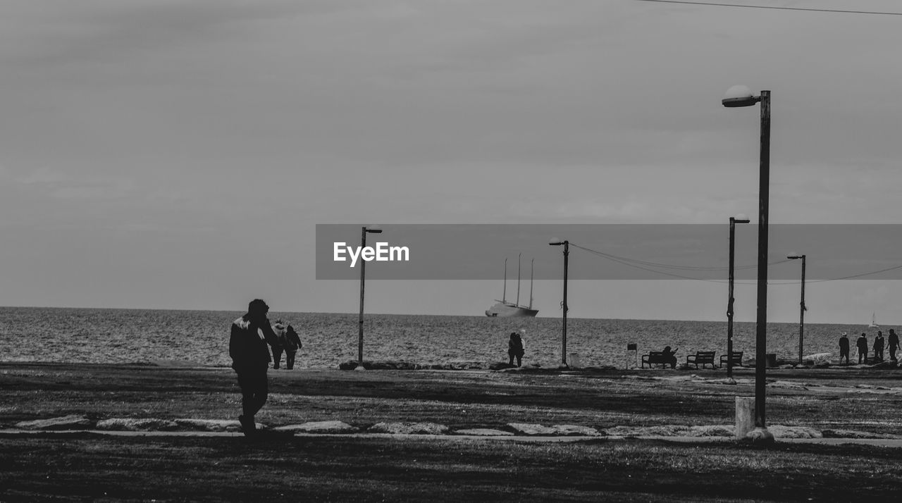 MAN STANDING ON BEACH AGAINST SEA