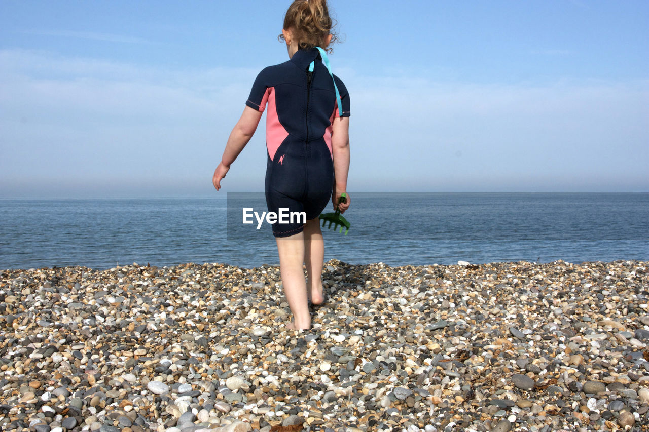 Full length of girl standing on beach against sky