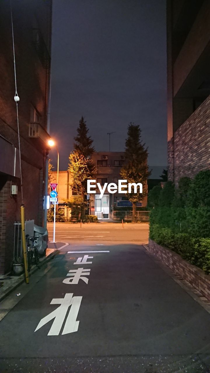 ROAD AMIDST BUILDINGS AT NIGHT