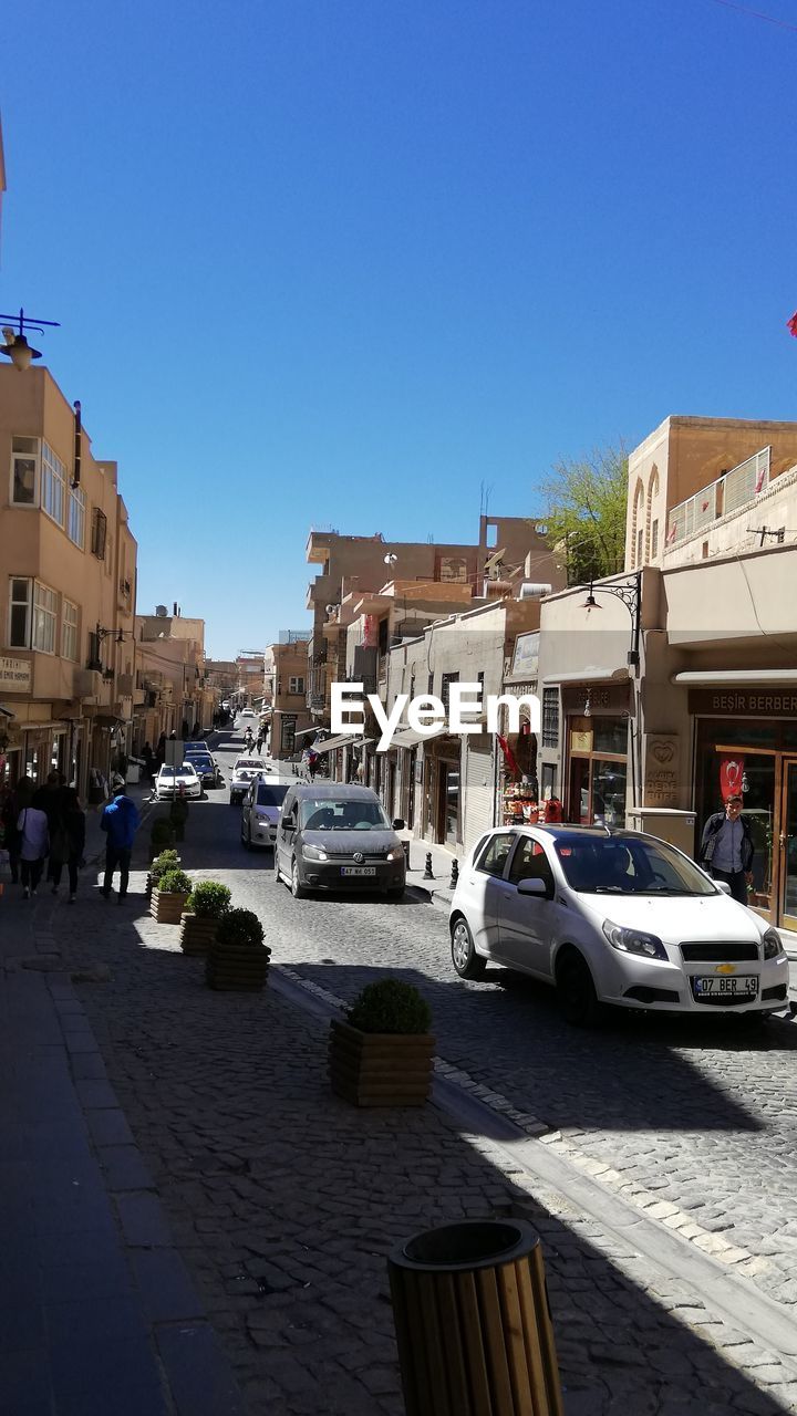 VIEW OF CITY STREET AND BUILDINGS AGAINST BLUE SKY