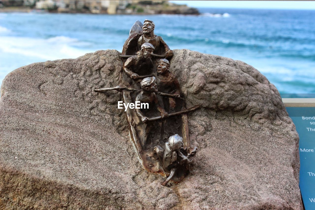 Sculptures on rock against sea