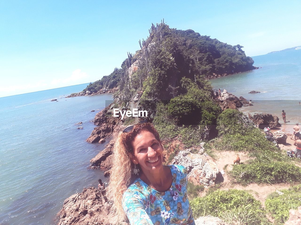 Portrait of smiling woman standing at beach against sky