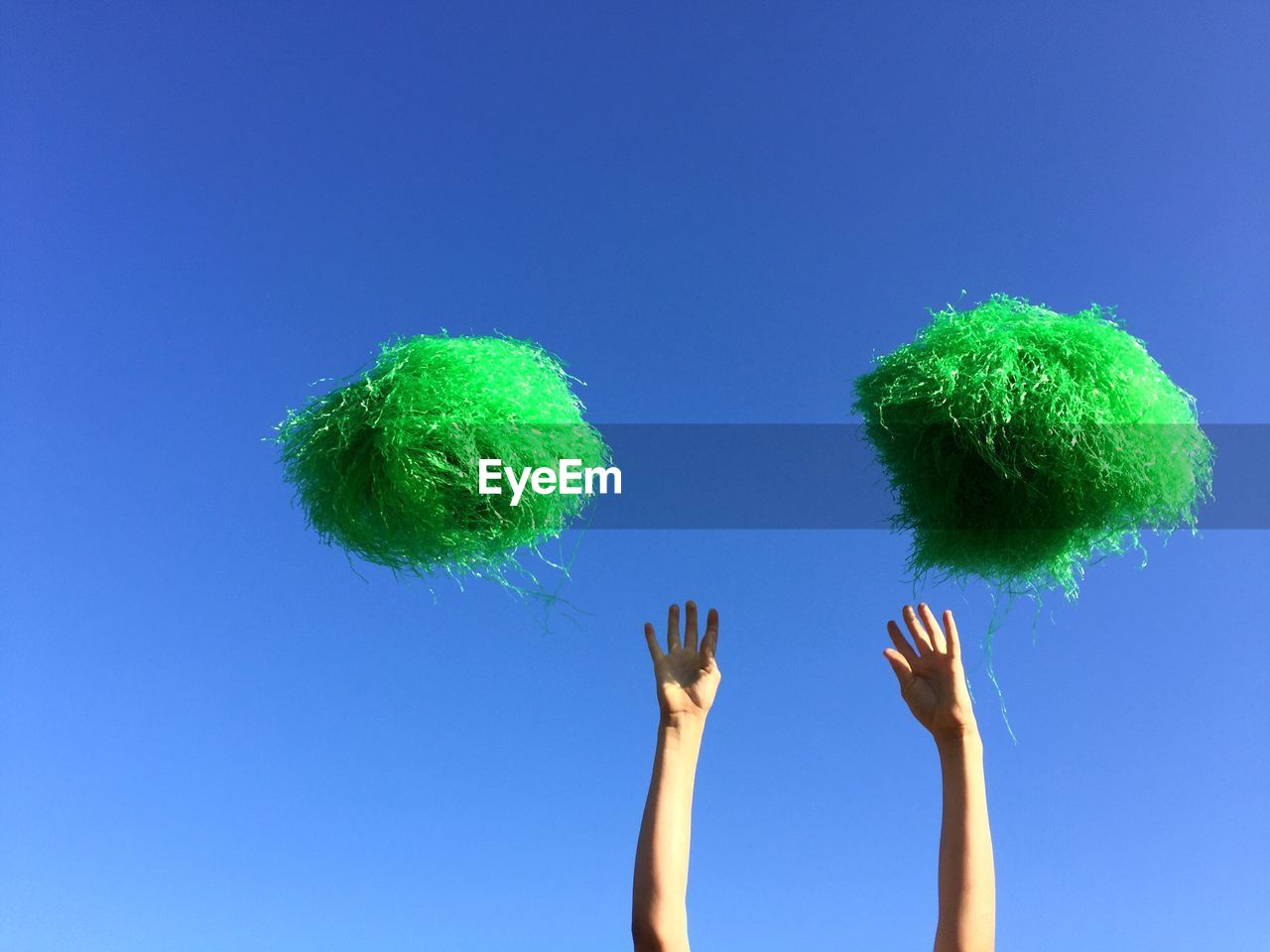 High section of cheerleader and pom poms