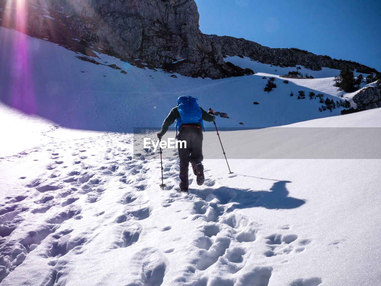 Rear view of person hiking on snow covered mountain