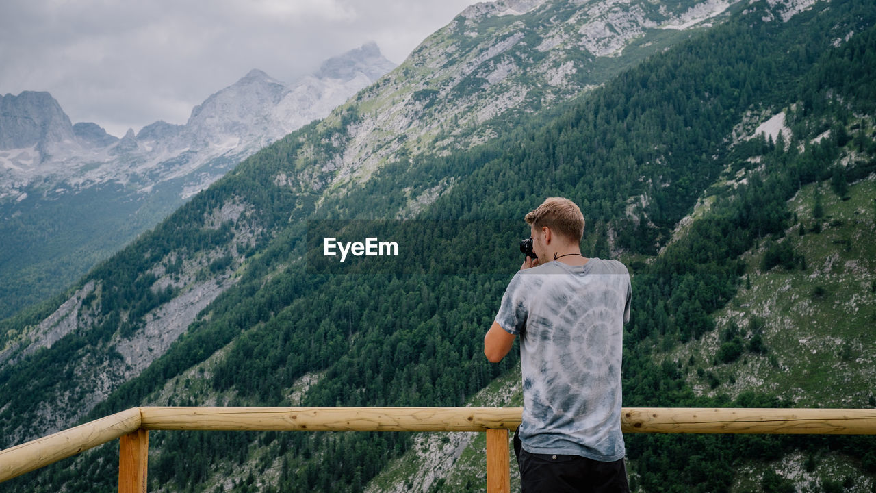 Rear view of man photographing mountains