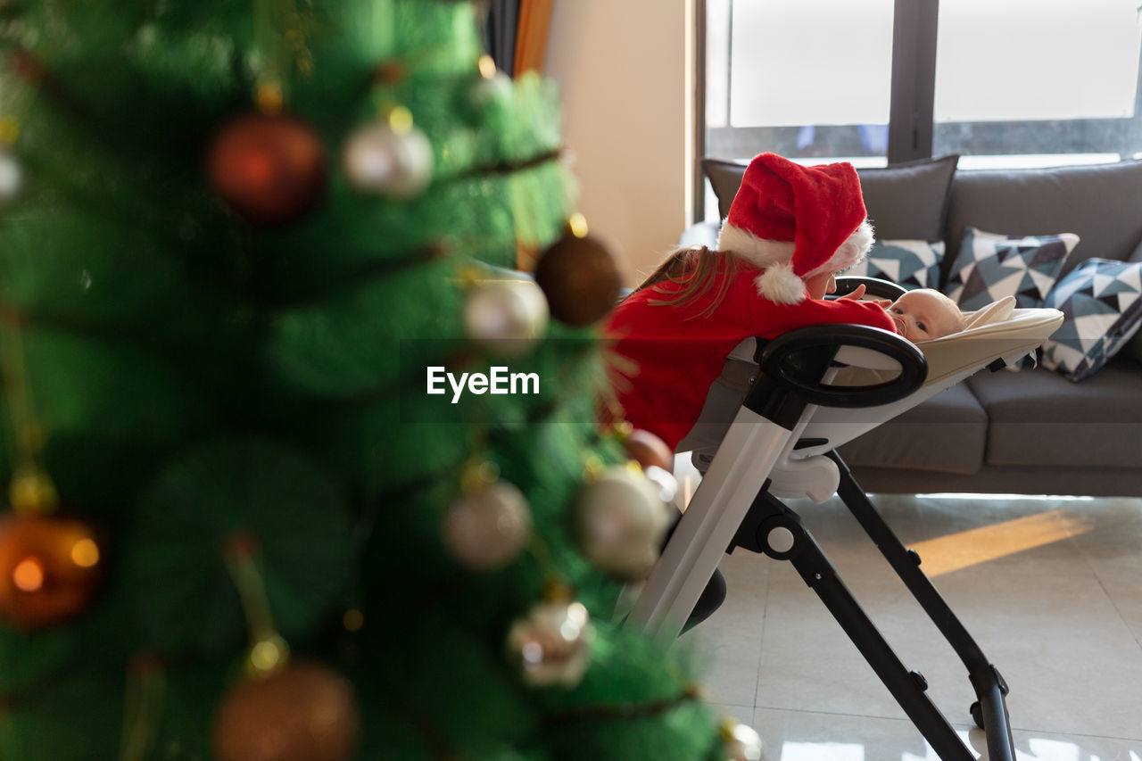 Cute girl wearing santa hat playing with sister at home