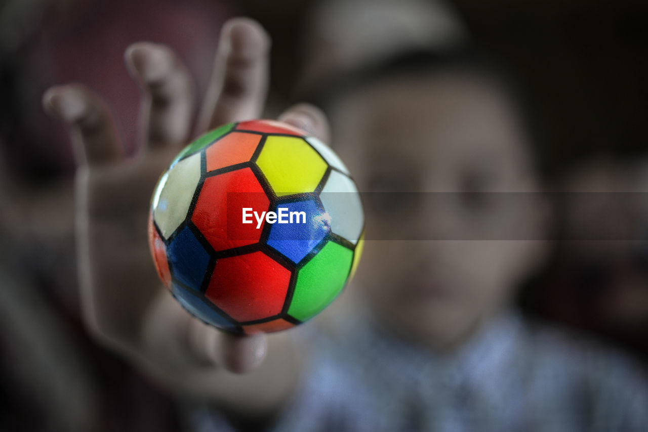 Defocused image of girl holding colorful ball