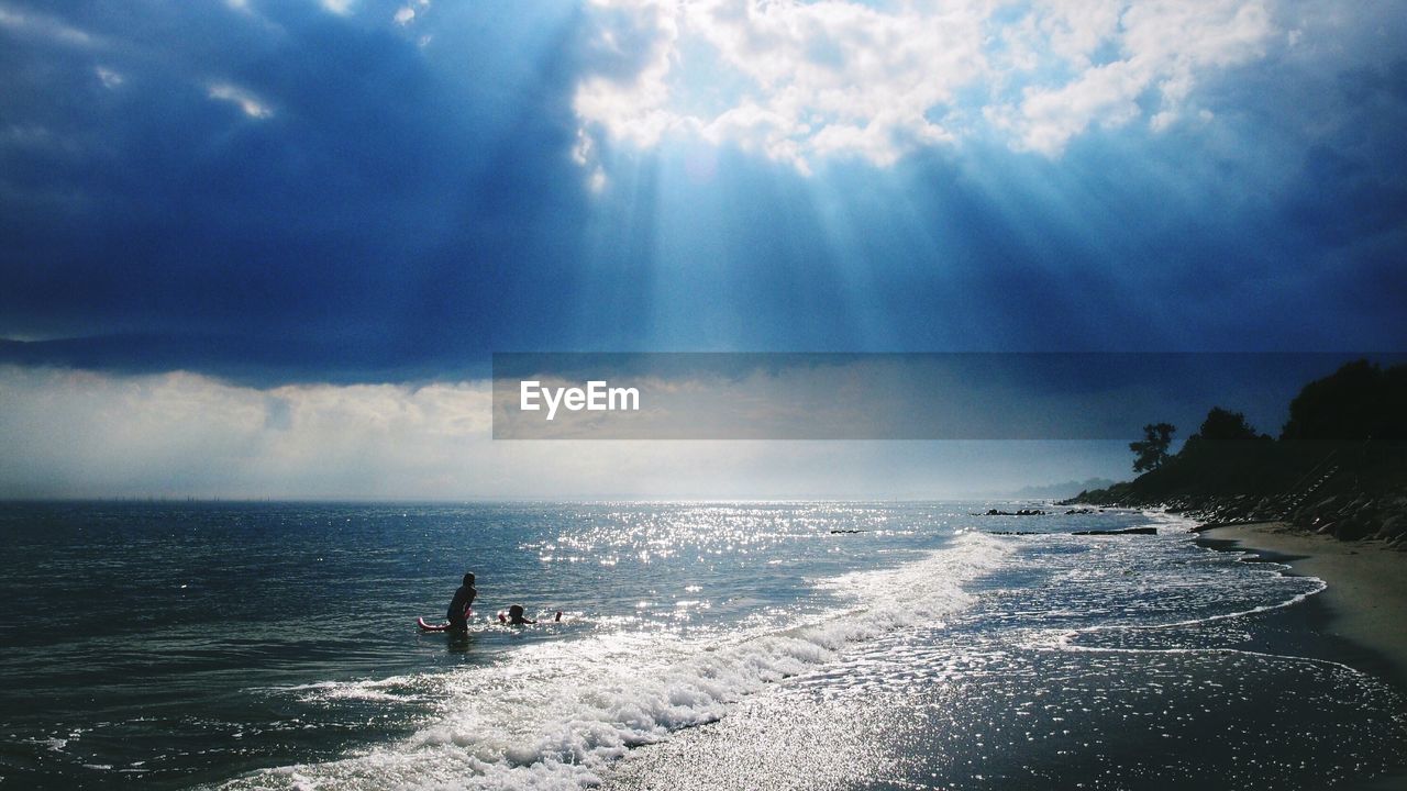 Scenic view of sea waves rushing towards shore against cloudy sky