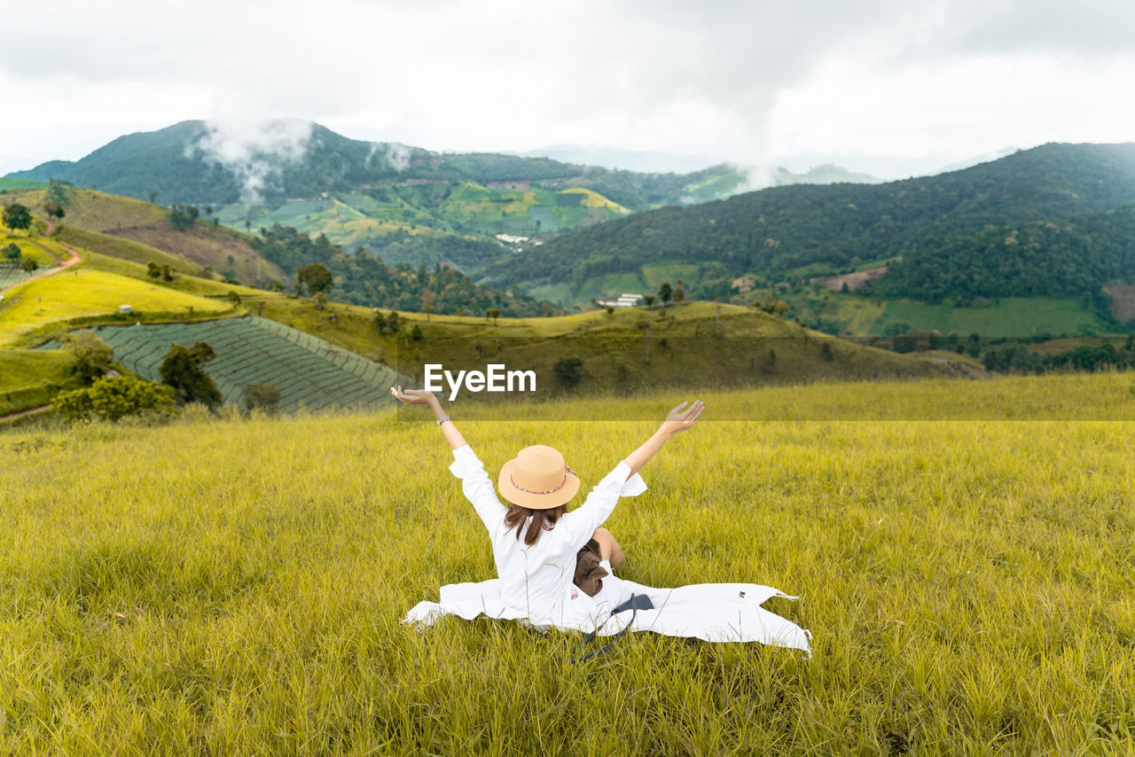 HIGH ANGLE VIEW OF WOMAN WALKING ON FIELD AGAINST MOUNTAIN