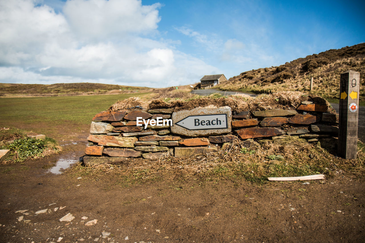 Wall with text on field against sky