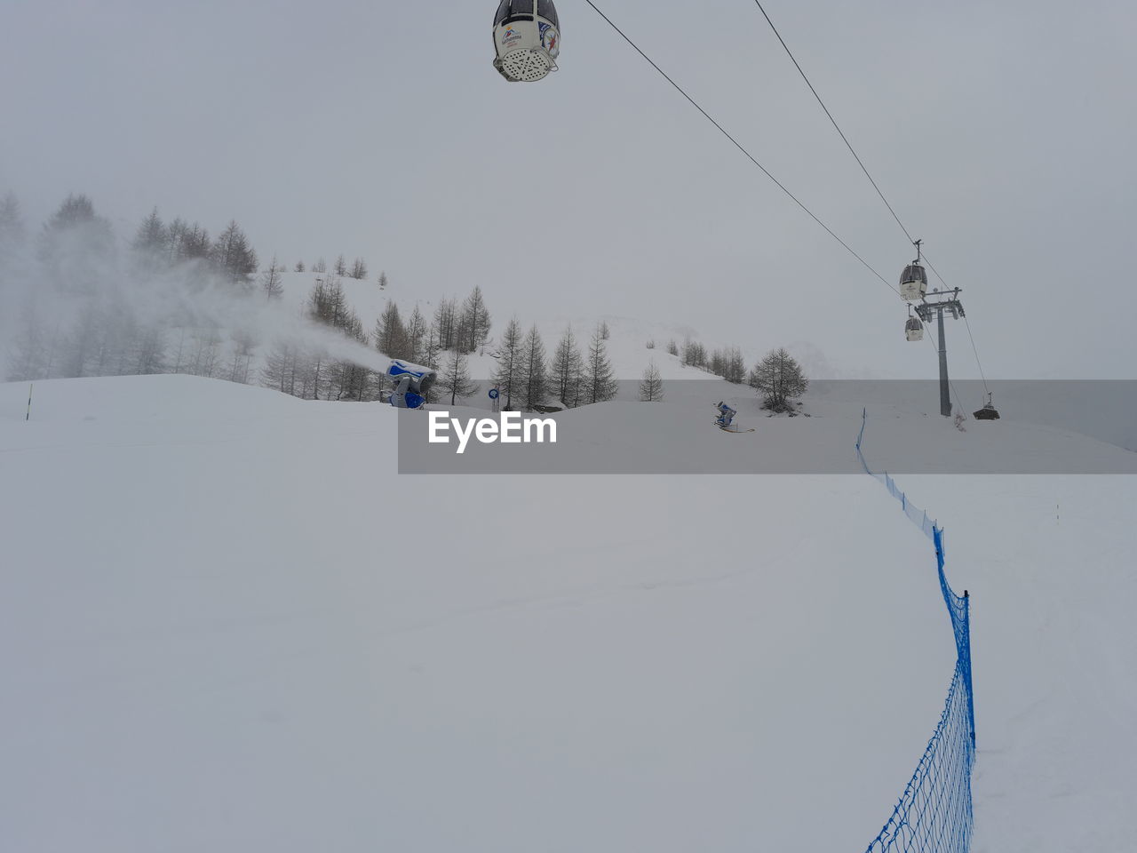 Close up of ski lift durino a snowfall with snow cannons belinda it ski on snow covered landscape