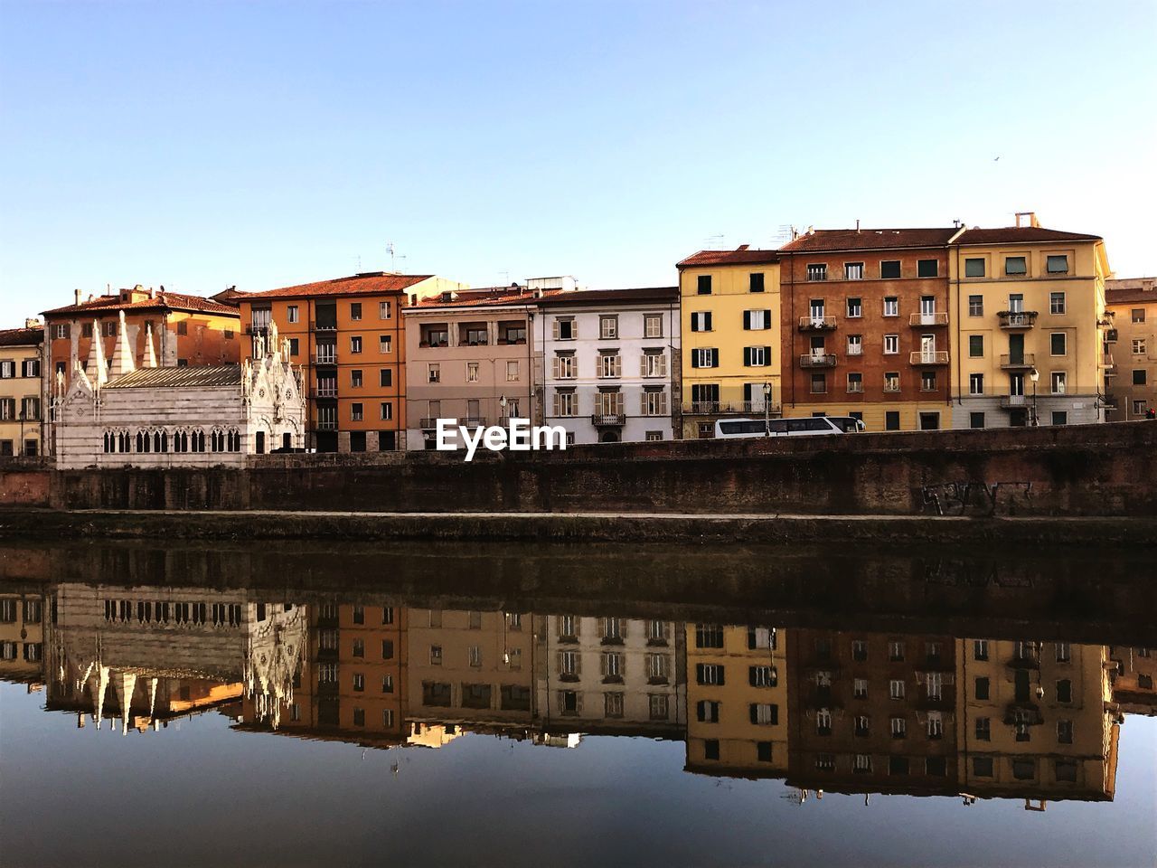 Reflection of buildings in city against clear sky