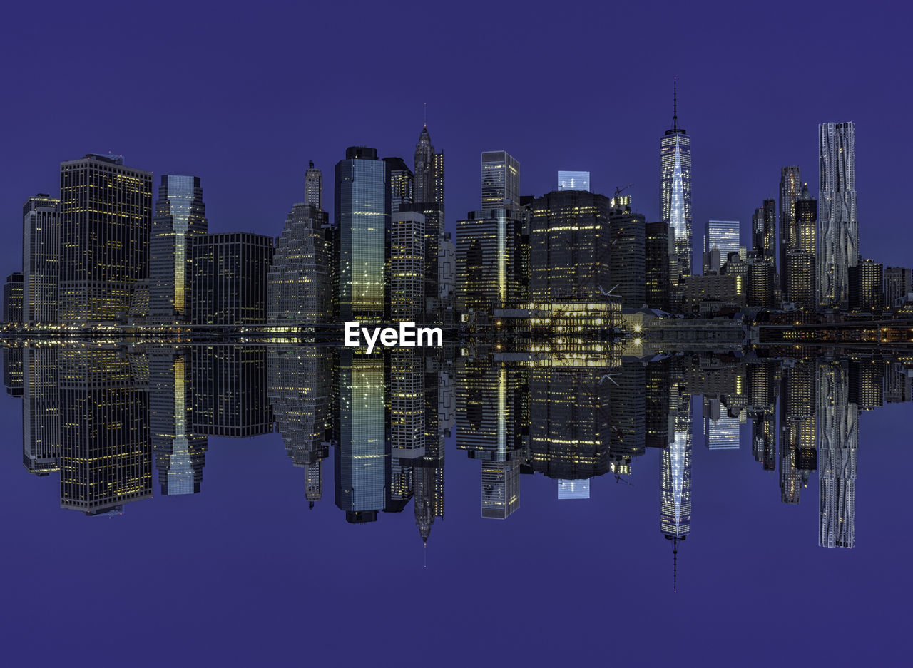 Illuminated manhattan skyline reflection in east river at night