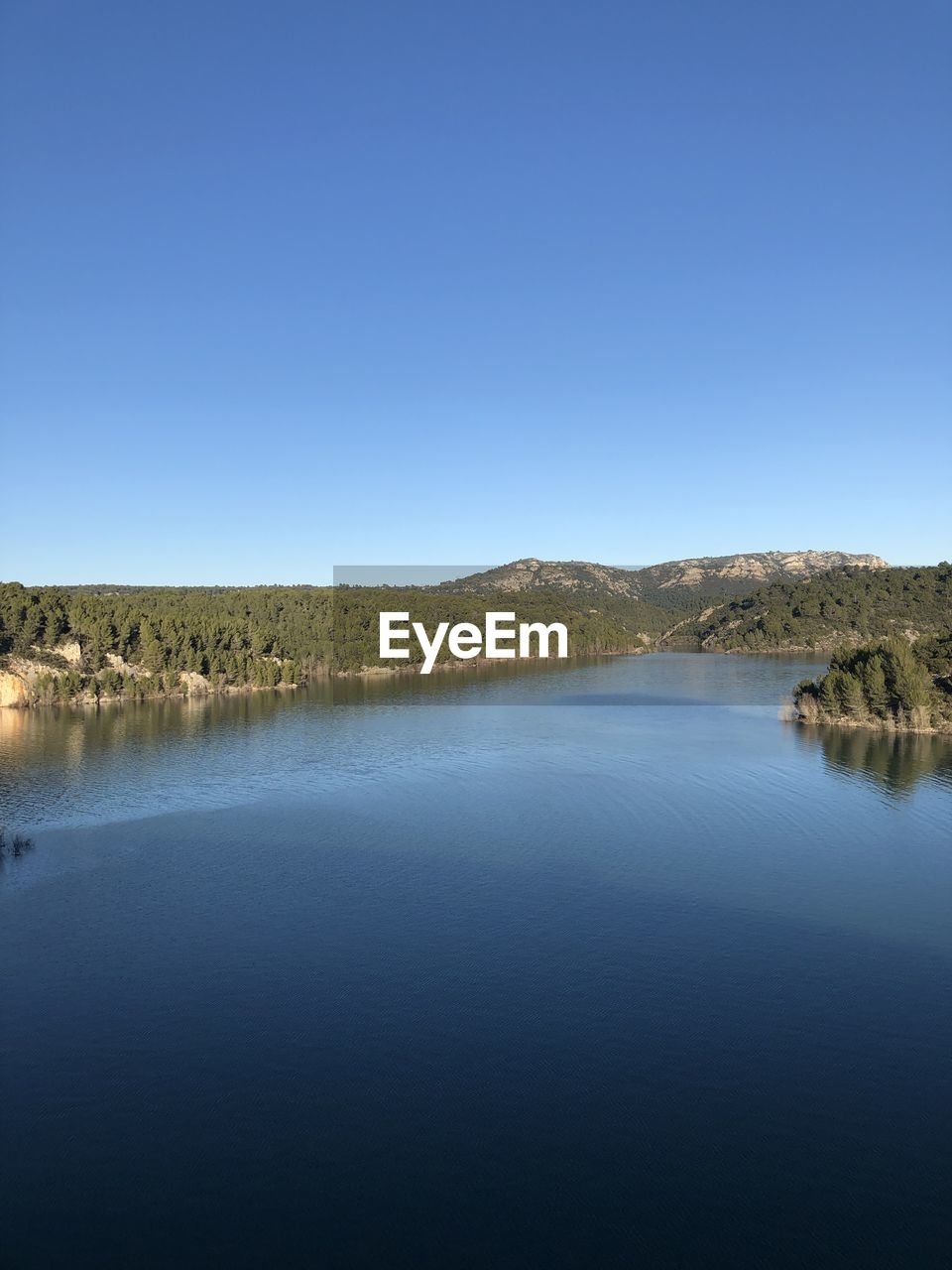 Scenic view of lake against clear blue sky