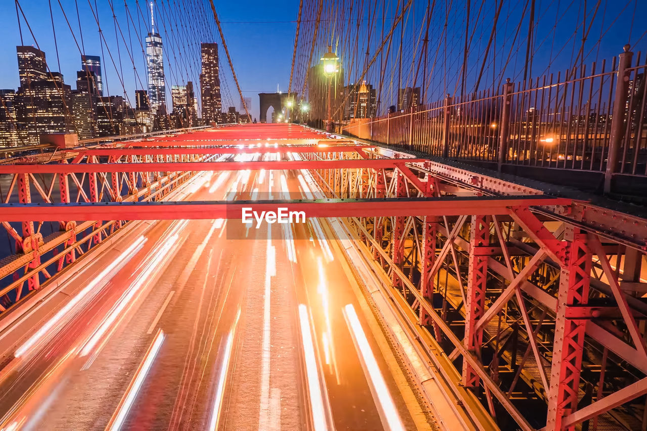 Blurred motion of cars on brooklyn bridge in city at night