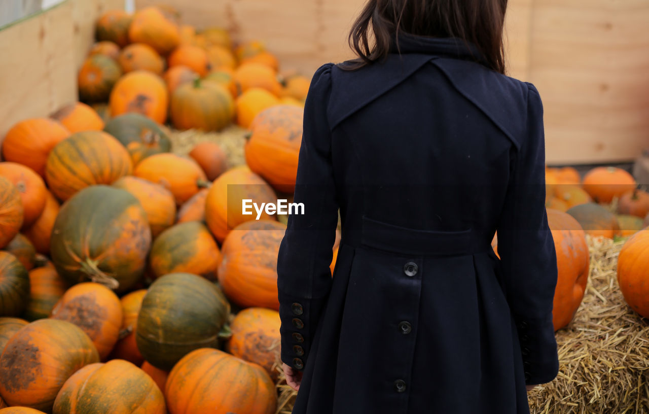 Rear view of woman standing against pumpkins