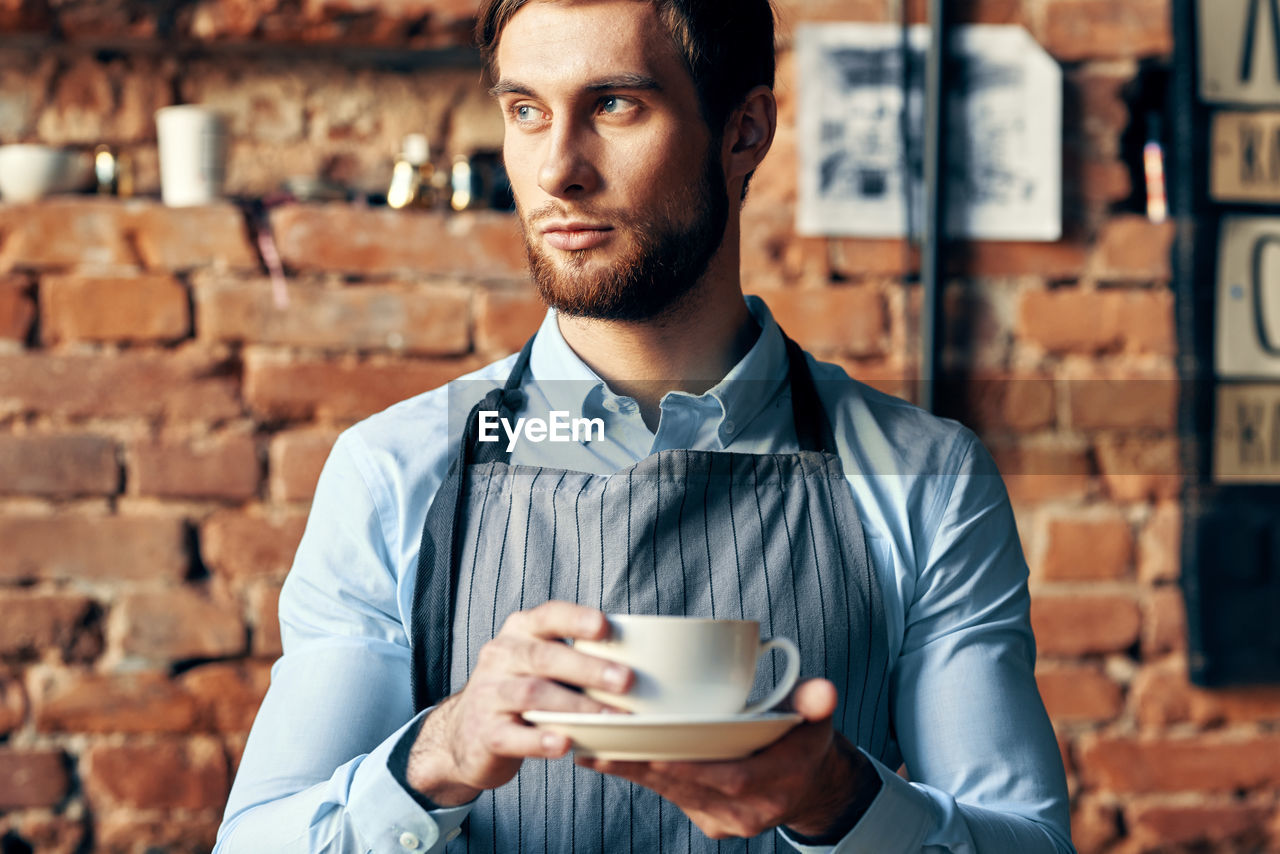 PORTRAIT OF YOUNG MAN WITH COFFEE CUP