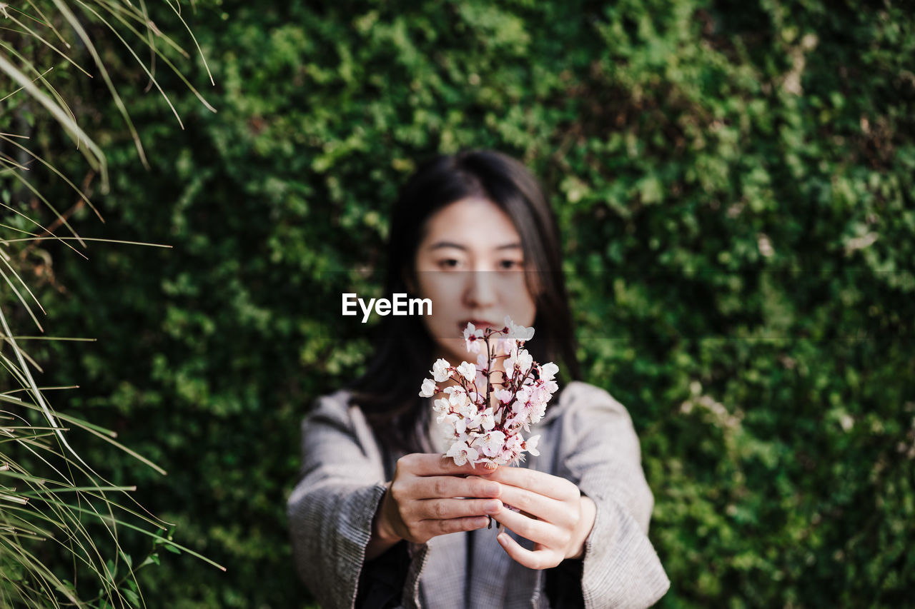 Beautiful chinese asian woman holding almond tree flowers.spring. selective focus on flowers