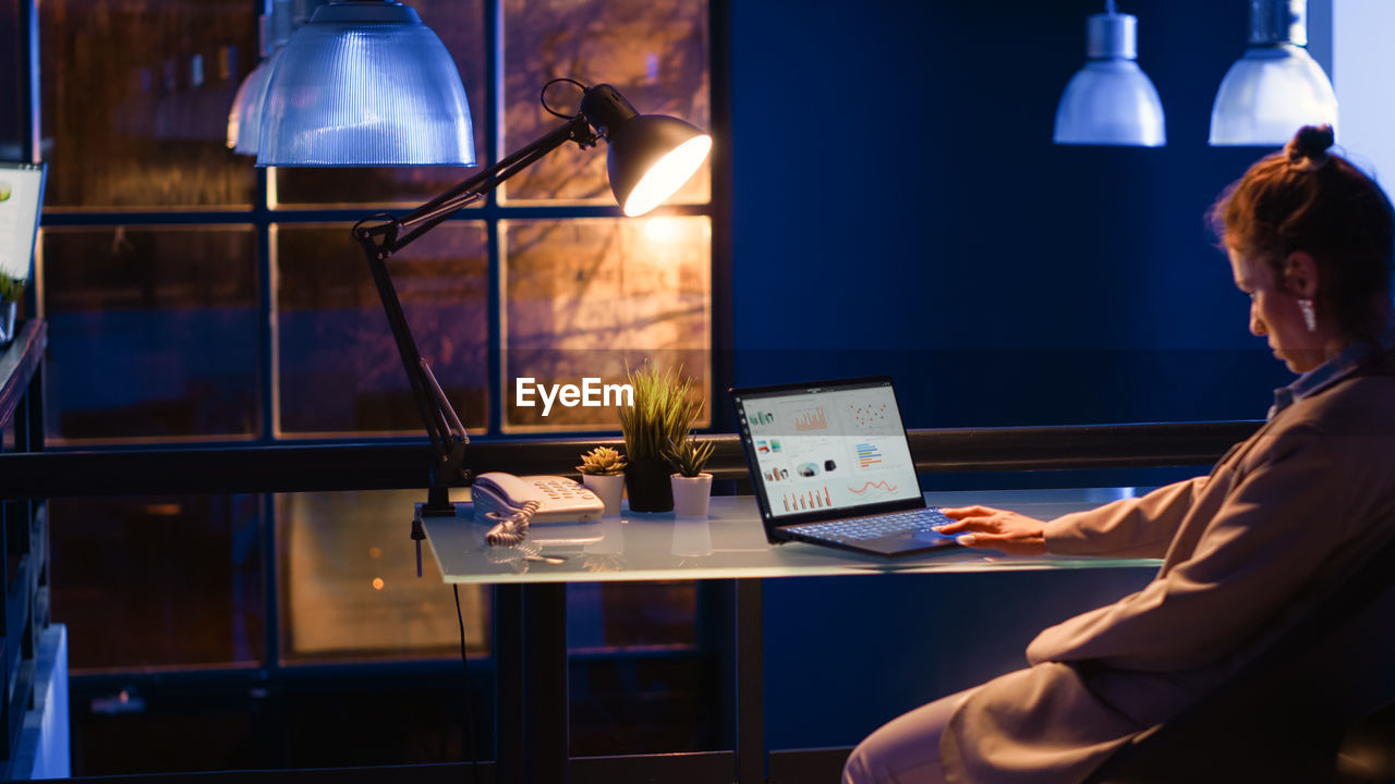 rear view of woman using laptop at table