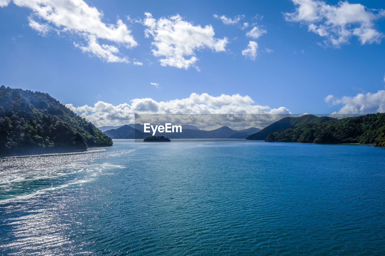 SCENIC VIEW OF SEA AND MOUNTAINS AGAINST BLUE SKY