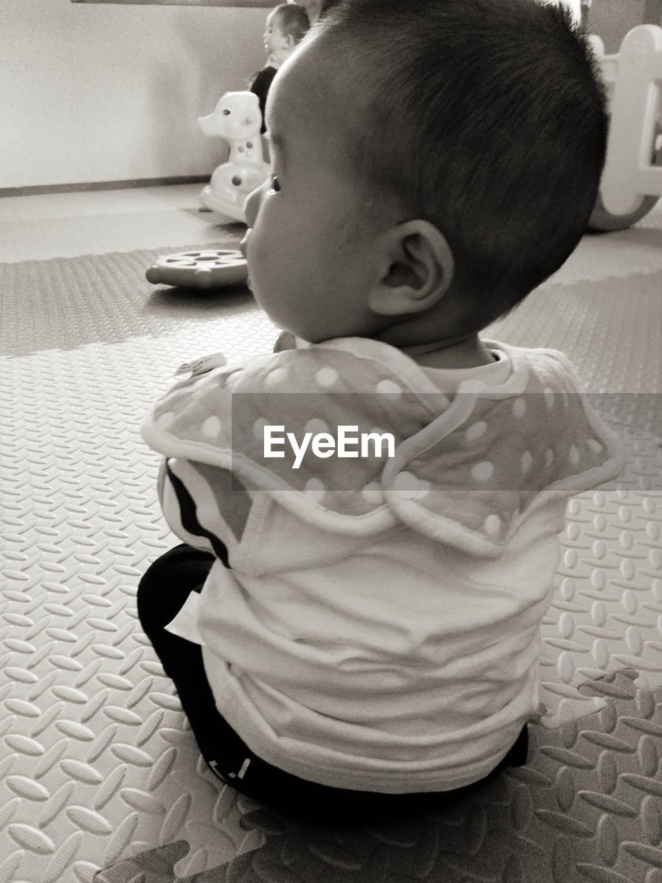 CUTE BABY GIRL SITTING ON SOFA AT HOME