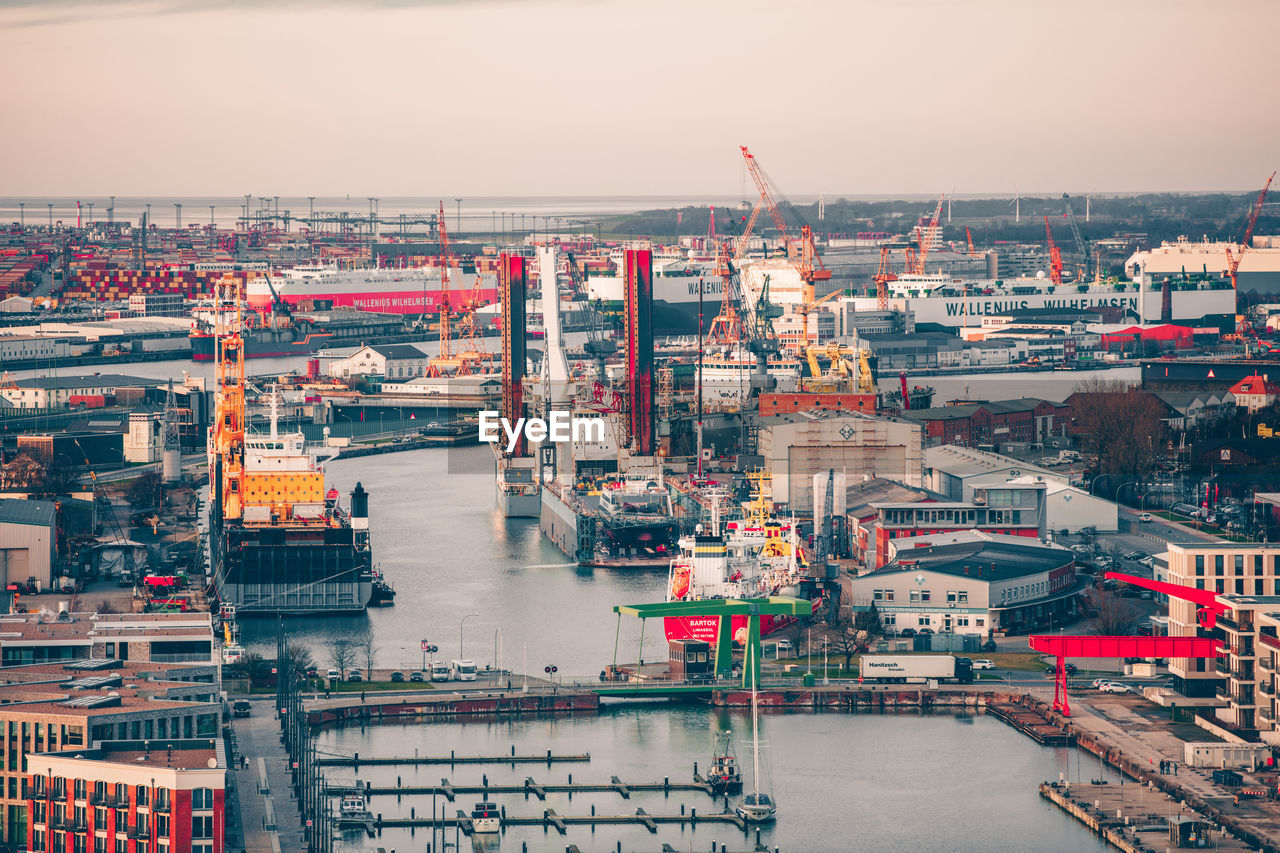 HIGH ANGLE VIEW OF CITYSCAPE BY SEA AGAINST SKY