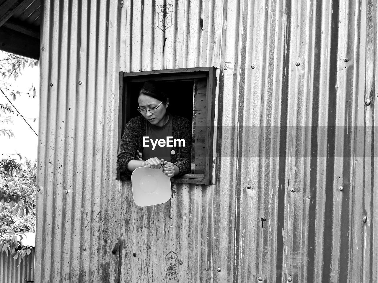 Woman cleaning container while peeking from window