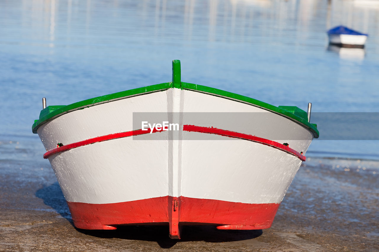 CLOSE-UP OF RED BOAT ON SEA SHORE