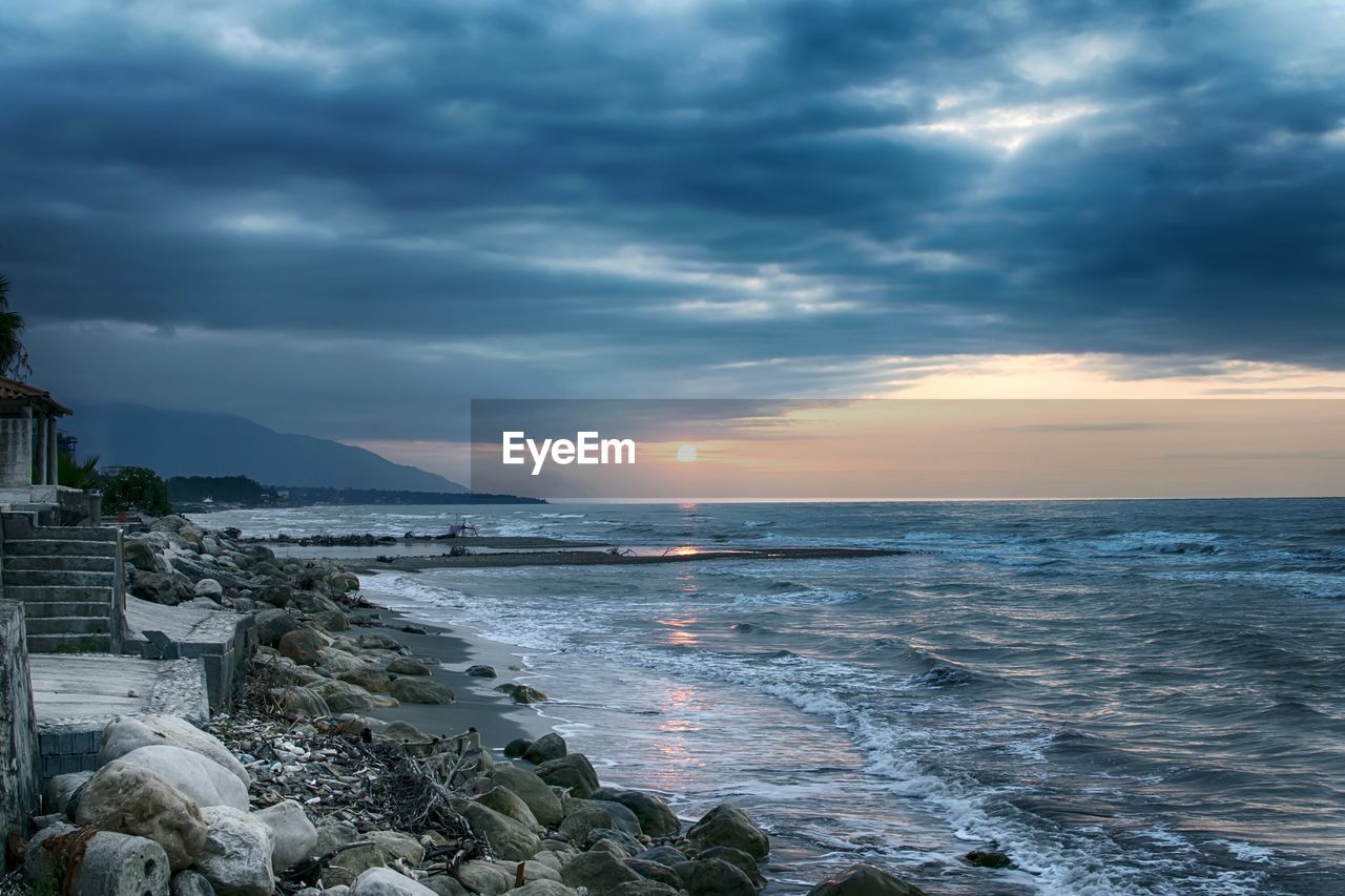 Scenic view of sea against cloudy sky at sunset