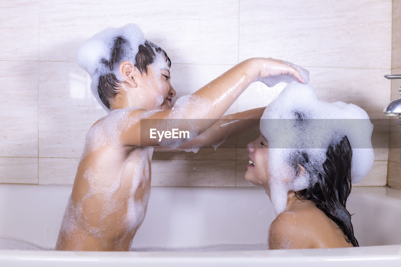 Side view of siblings in bathroom at home