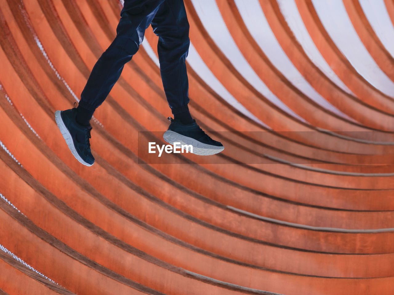 Close-up view of a boy jumping with orange curves background 