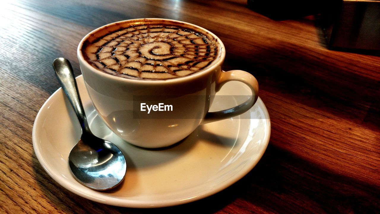 CLOSE-UP OF COFFEE CUP AND SPOON ON TABLE