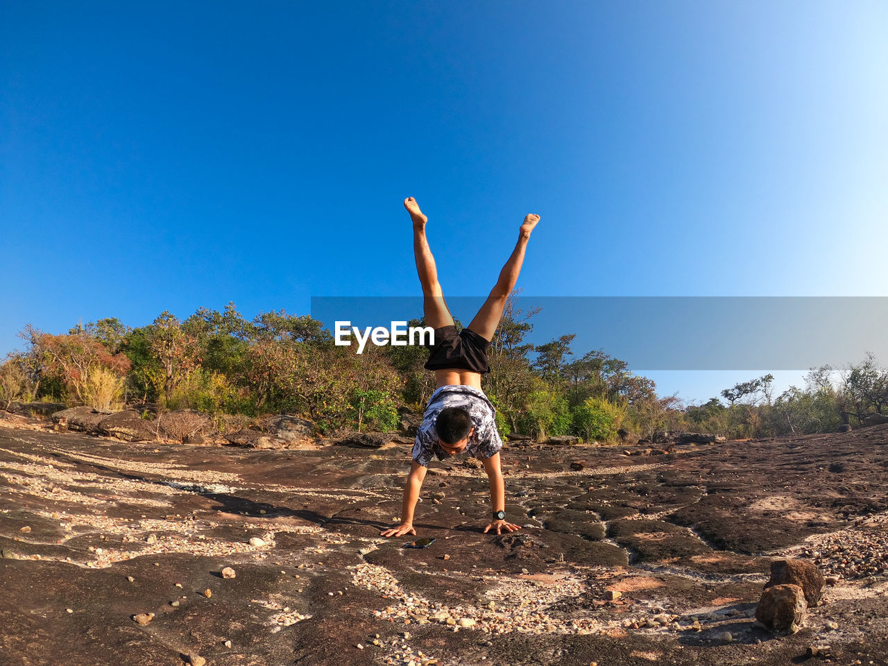 FULL LENGTH REAR VIEW OF MAN WALKING ON LAND AGAINST CLEAR SKY