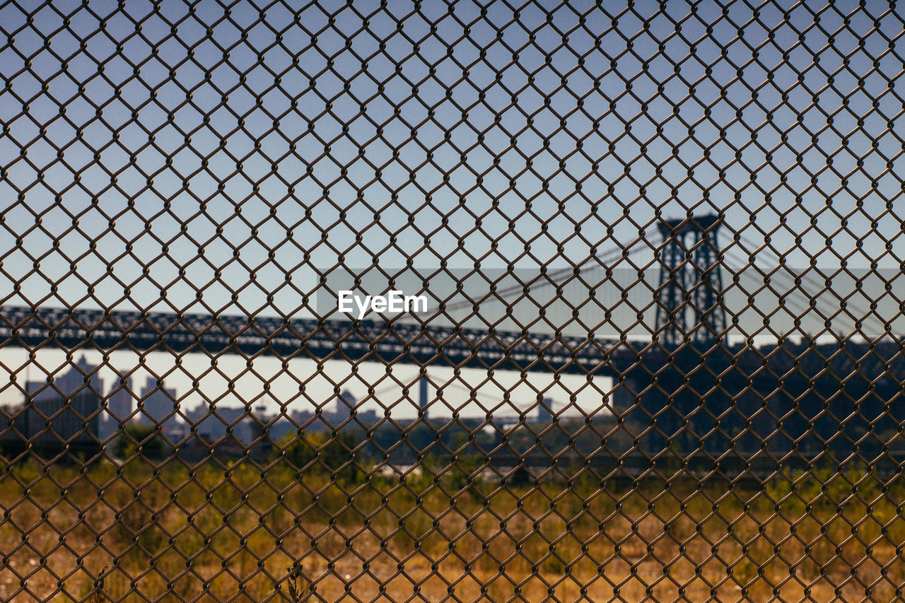 Williamsburg bridge against clear sky seen through fence