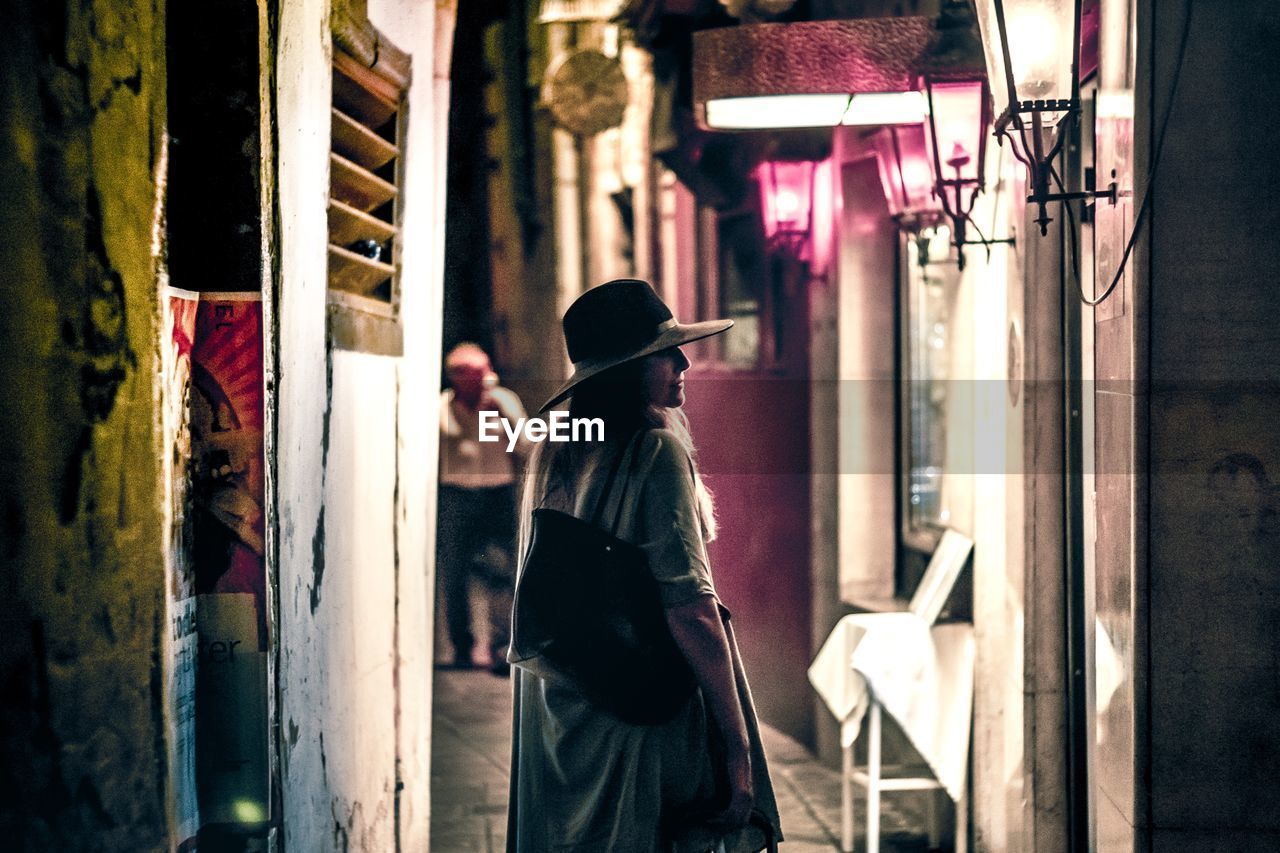 REAR VIEW OF MAN AND WOMAN WALKING ON STREET