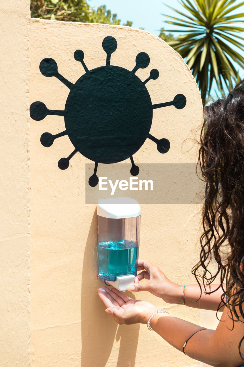 Cropped hand of woman using hand sanitizer outdoors