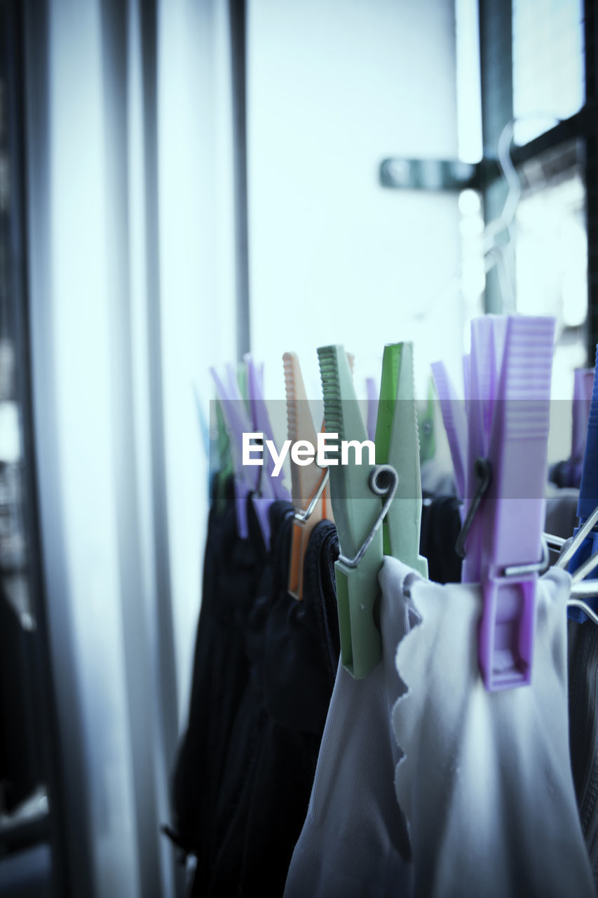 clothing, indoors, fashion, room, hanging, blue, coathanger, business, retail, clothing store, no people, shopping, store, textile, selective focus, rack, window, clothes rack, business finance and industry, variation, large group of objects