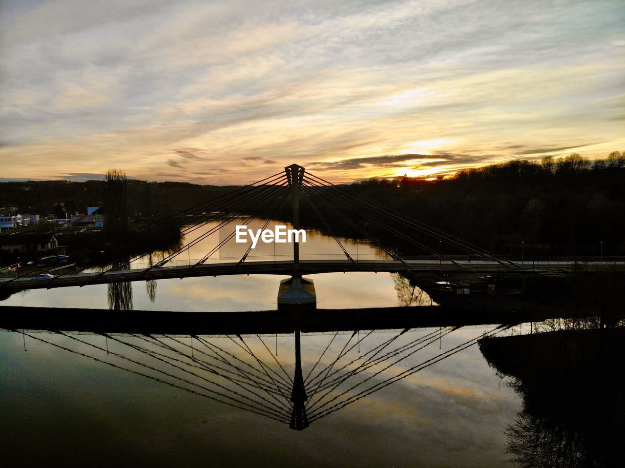 SILHOUETTE BRIDGE OVER LAKE AGAINST SKY AT SUNSET