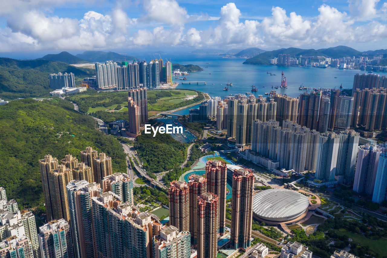 HIGH ANGLE VIEW OF CITY BY SEA AGAINST SKY