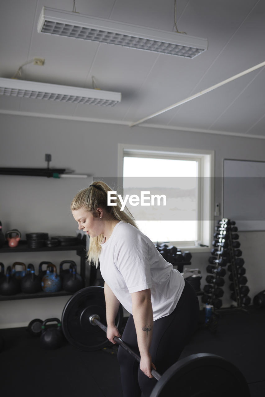 Mid adult woman lifting barbell in gym