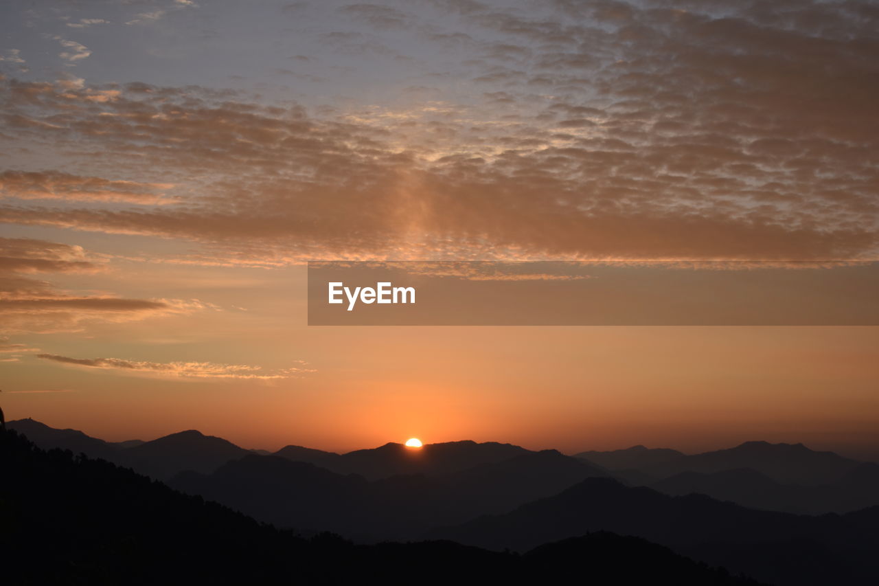 Scenic view of silhouette mountains against romantic sky at sunset