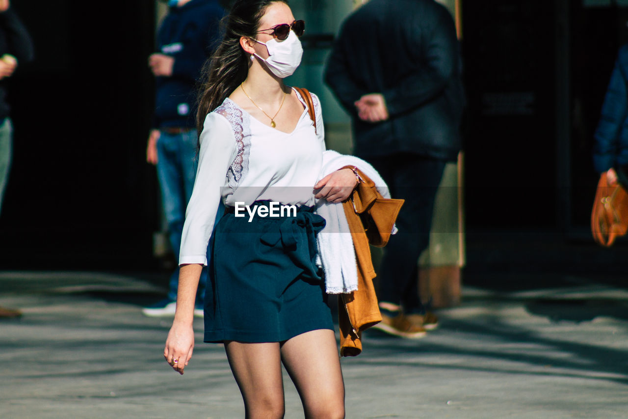 REAR VIEW OF WOMAN WITH UMBRELLA WALKING ON STREET