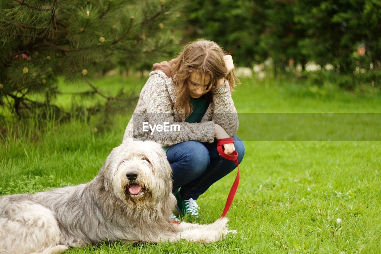Young woman with bearded collie on grassy field at park