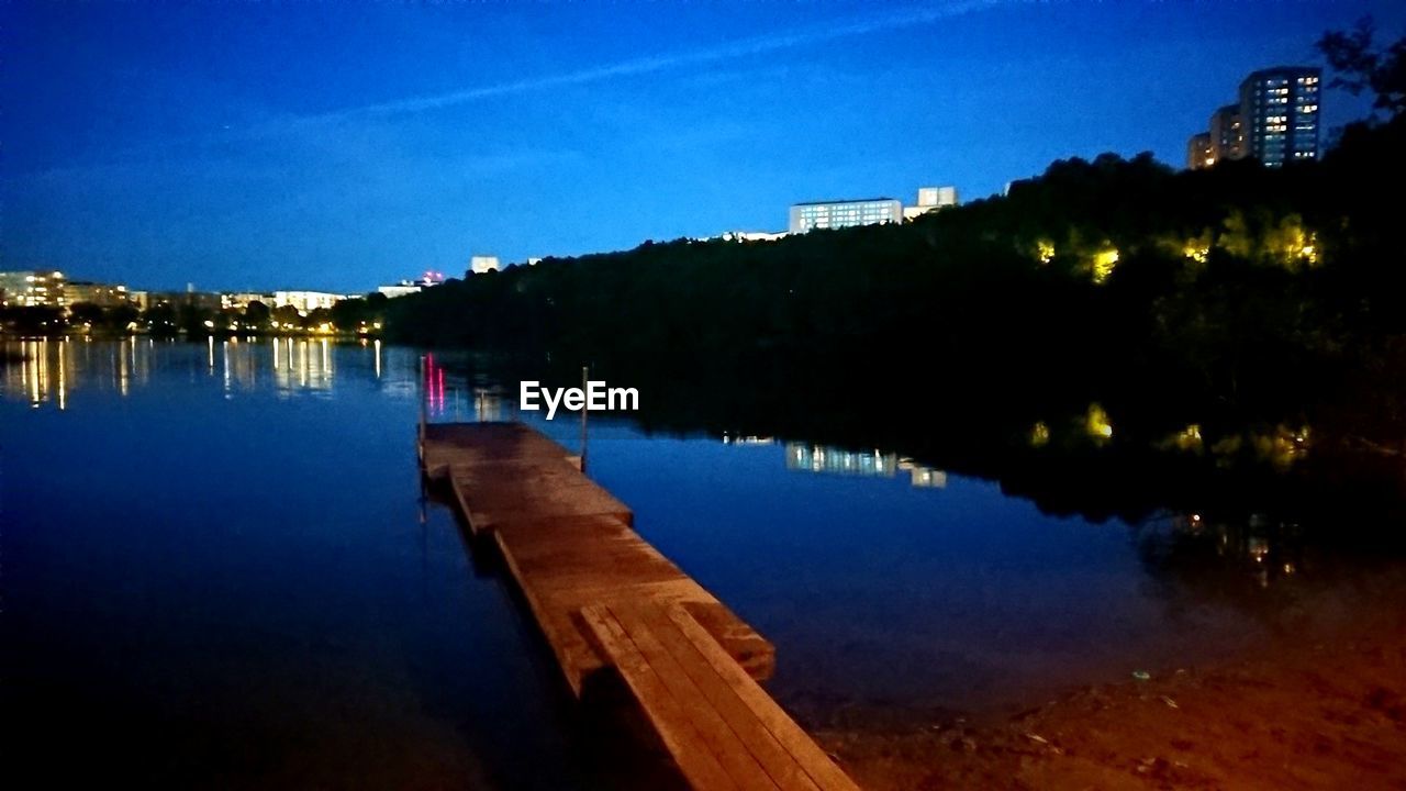 SCENIC VIEW OF RIVER BY ILLUMINATED CITY AGAINST SKY AT NIGHT