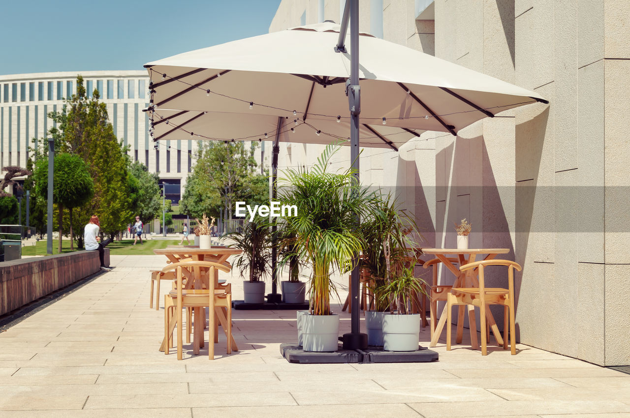 CHAIRS AND TABLES BY BUILDING AGAINST CLEAR SKY