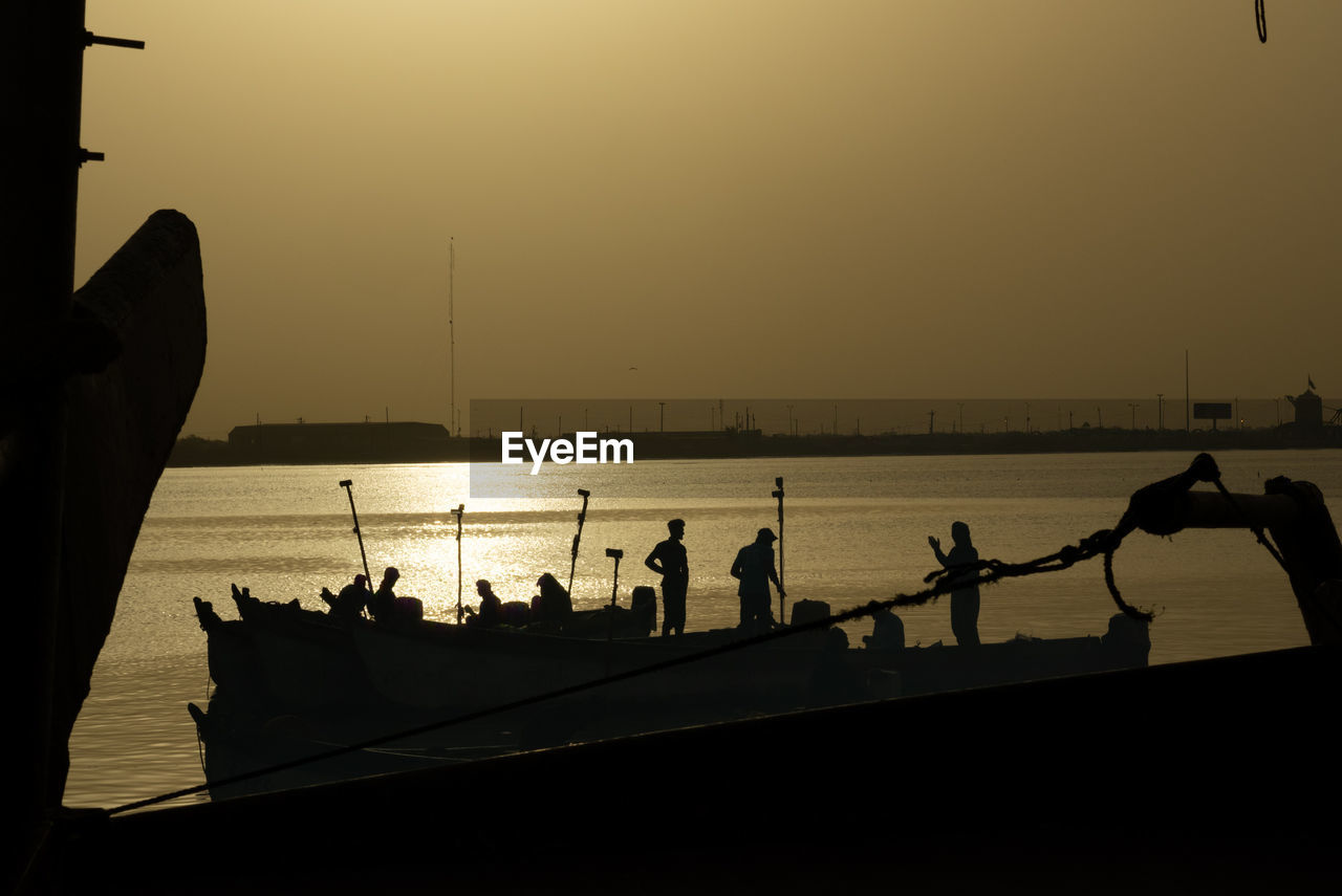 silhouette, water, sky, nautical vessel, transportation, sunset, nature, sea, evening, dusk, group of people, mode of transportation, vehicle, men, beauty in nature, ship, outdoors, lifestyles, horizon, travel, boat