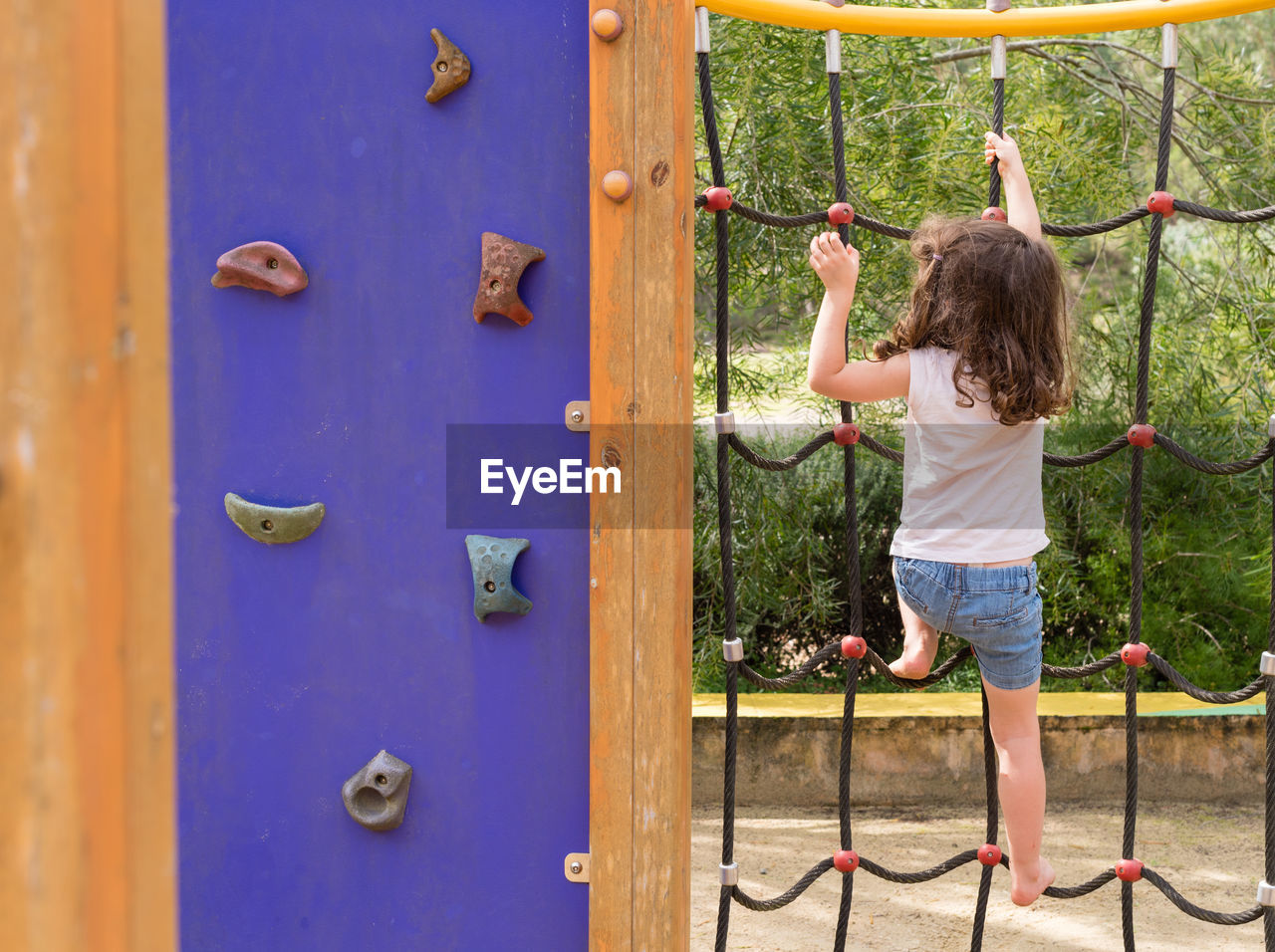 Rear view of girl climbing on jungle gym at playground