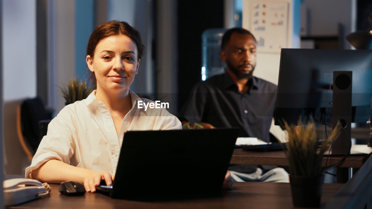 business colleagues using laptop at desk in office